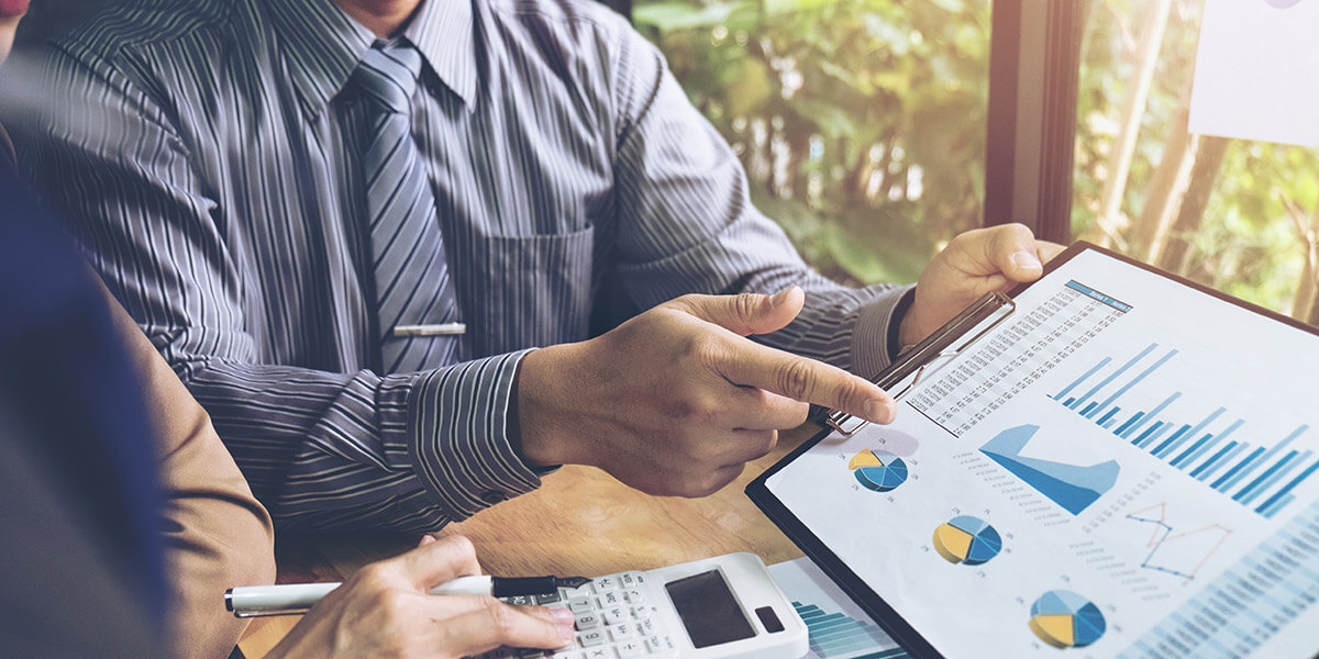A man points to graphs on a clipboard.